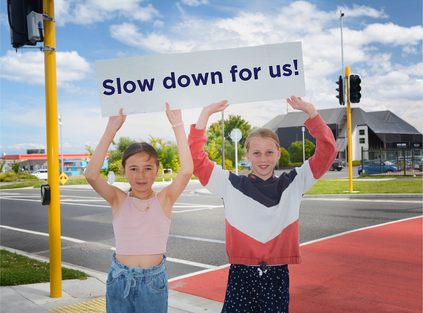 School kids with sign saying Slow Down For Us