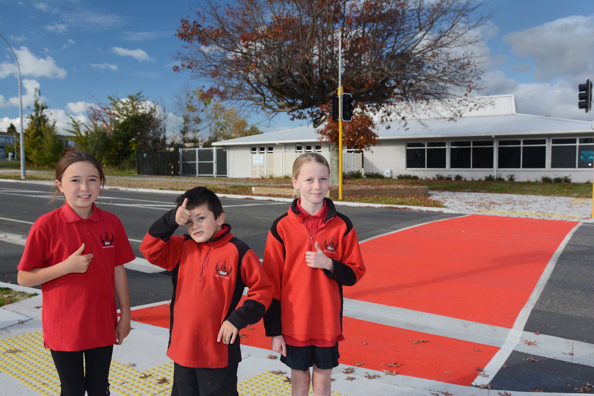 Taupo Primary students giving the thumbs up at the bright red addition to the traffic lights by the school.  